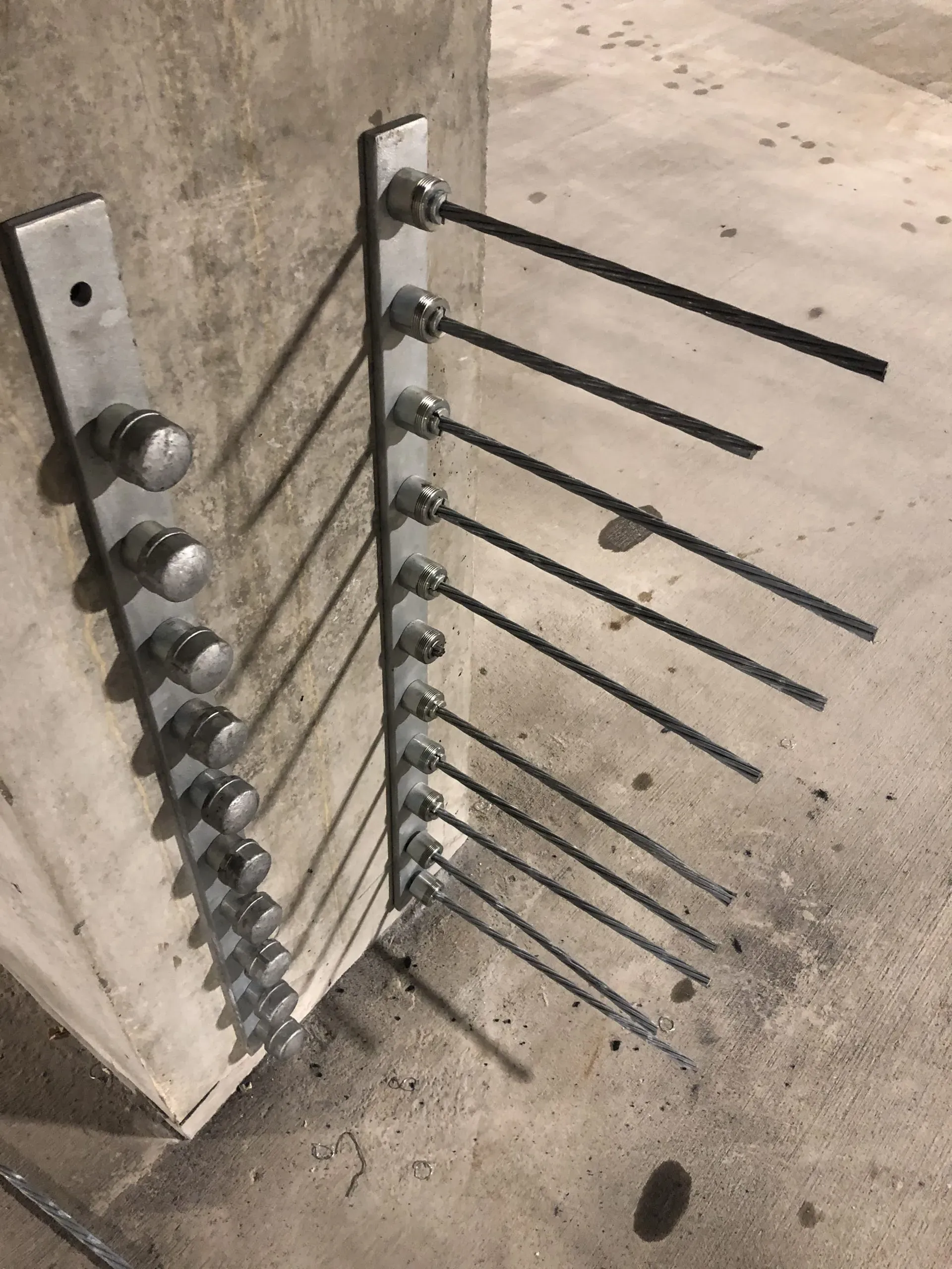 Close-up of post-tensioned cable anchors secured to a concrete column as part of a structural retrofit system.