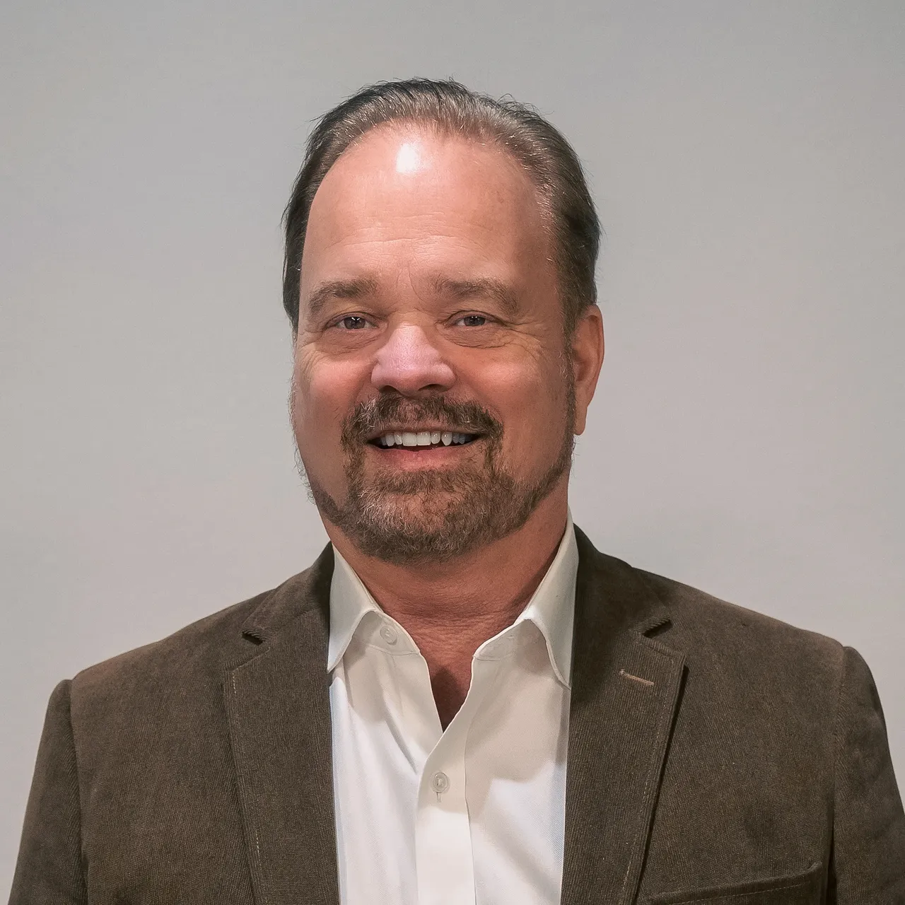 Rick Thompson in a blazer and white shirt, smiling as the CEO of the post-tensioning company.